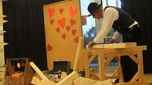 Richard Betz, Zimmerermeister aus Ersen, erzählt den Schülern vom Handwerk und baut dabei geschäftig auf der Bühne herum. Was das wohl wird? Foto: Theresa Schiffl