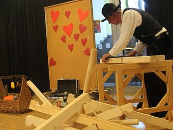 Richard Betz, Zimmerermeister aus Ersen, erz&auml;hlt den Sch&uuml;lern vom Handwerk und baut dabei gesch&auml;ftig auf der B&uuml;hne herum. Was das wohl wird? Foto: Theresa Schiffl