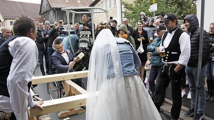 Benni Gemählich mit seiner Frau beim Holzbearbeiten am Stand seines Arbeitgebers anlässlich der Hochzeit, rechts mit Tracht der Firmenbesitzer Stefan Singer