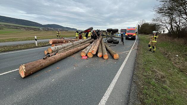 Traktor mit Rückewagen voller Stämme kippt um - Fahrer verletzt