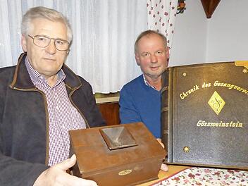 Peter Helldörfer (l.) und Konrad Schrüfer mit zwei besonderen Schätzen des Männergesangvereins Gößweinstein. Helldörfer zeigt die Wahlurne die darüber entschied ob ein neuer Sänger aufgenommen wurde und Schrüfer präsentiert die Vereinschronik die 1895 beginnt.  Foto: T. Weichert