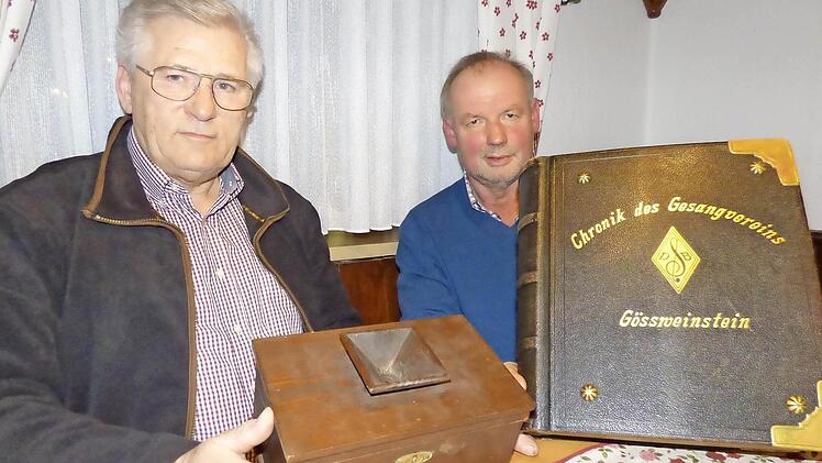 Peter Helldörfer (l.) und Konrad Schrüfer mit zwei besonderen Schätzen des Männergesangvereins Gößweinstein. Helldörfer zeigt die Wahlurne die darüber entschied ob ein neuer Sänger aufgenommen wurde und Schrüfer präsentiert die Vereinschronik die 1895 beginnt.  Foto: T. Weichert