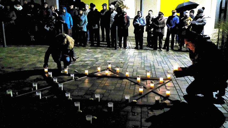 Während der Gedenkstunde wurden die Kerzen des jüdischen Davidsterns in der nasskalten Dunkelheit entzündet. Foto: Gerd Schaar