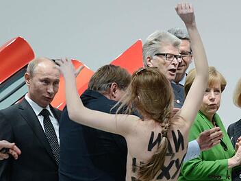 Eine nackte Demonstrantin steht am Montag in Hannover beim Eröffnungsrundgang der Hannover Messe vor Bundeskanzlerin Angela Merkel (2.v.r., CDU) und Russlands Staatspräsident Wladimir Putin (l). Foto: Jochen Lübke/dpa