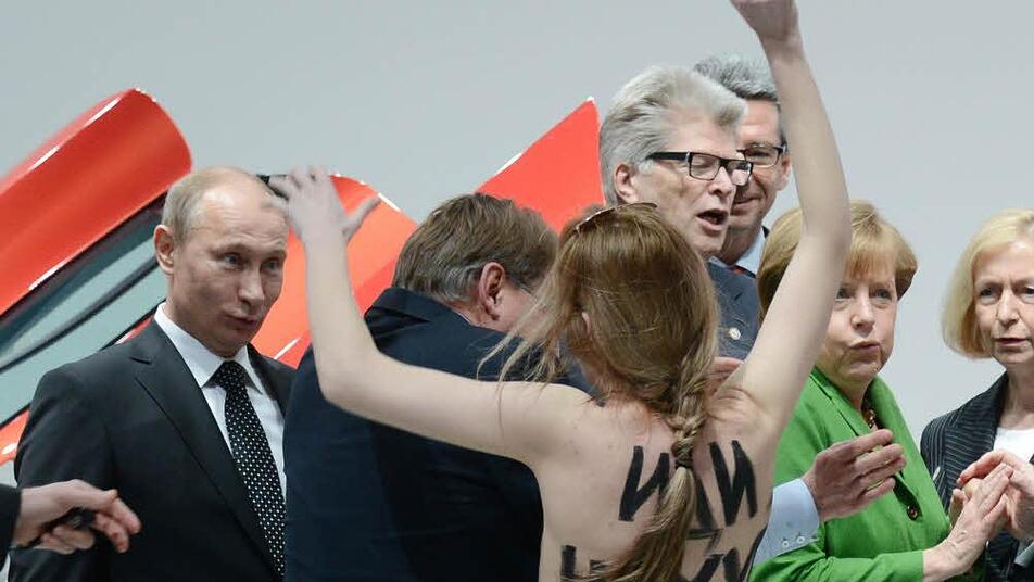 Eine nackte Demonstrantin steht am Montag in Hannover beim Eröffnungsrundgang der Hannover Messe vor Bundeskanzlerin Angela Merkel (2.v.r., CDU) und Russlands Staatspräsident Wladimir Putin (l). Foto: Jochen Lübke/dpa