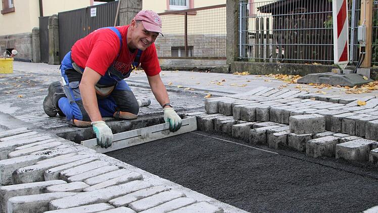 Hier wird noch ausgebessert: Dieter Schmitt setzt die letzten Pflastersteine auf dem Teilstück Sparkassenstraße/Sinnaustraße. Fotos: Ulrike Müller