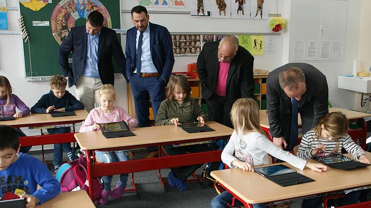 Der offizielle Startschuss für das digitale Lernern an der Johann-Peter-Wagner-Schule in Theres fiel gestern beim Besuch der drei Bürgermeister Peter Kraus, Holger Baunacher und Matthias Schneider und des Elternbeiratsvorsitzenden Michael Winkler, die sich hier von den Erst- dn Zweitklässlern in die entsprechenden Lernprogramme einweisen lassen. Foto: Sabine Weinbeer