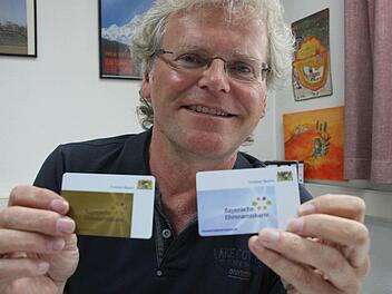 Herbert Köhl zeigt die beiden Versionen der Bayerischen Ehrenamtskarte. Foto: Dieter