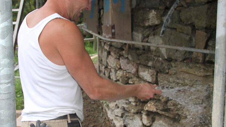Thomas Korsch spritzt das Mauerwerk mit Wasser ab.