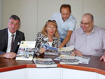 Blättern in der Chronik zum 25-jährigen Stadtrecht in einem Familienalbum (von links): Bürgermeister Gerhard Preß, Ingrid Ott, Günther Benning und Büchereileiter Michael Scholz. Foto: Rainer Lutz