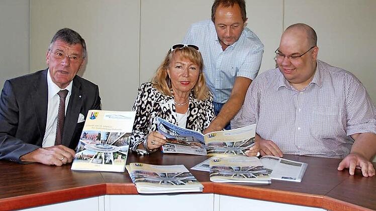 Blättern in der Chronik zum 25-jährigen Stadtrecht in einem Familienalbum (von links): Bürgermeister Gerhard Preß, Ingrid Ott, Günther Benning und Büchereileiter Michael Scholz. Foto: Rainer Lutz