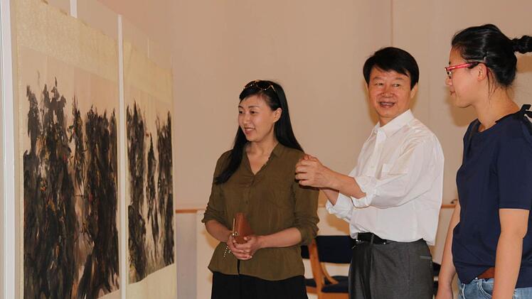 Der chinesische K&uuml;nstler So Meilun erl&auml;utert Organisatorin Mu Zhang (rechts) seine Bilder. Foto: Kerstin V&auml;th