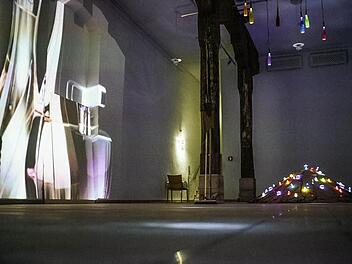 Zwei Besonderheiten der Ausstellung "Glas meets light"in der alten Markthalle: Der mit Glasflakons versehene Sandhaufen und der "Riesenflakon an der Wand". Foto: Stephan Amm