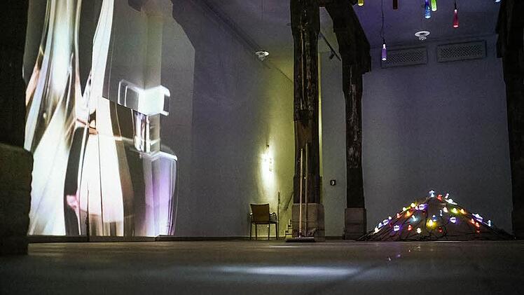 Zwei Besonderheiten der Ausstellung "Glas meets light"in der alten Markthalle: Der mit Glasflakons versehene Sandhaufen und der "Riesenflakon an der Wand". Foto: Stephan Amm