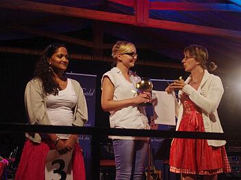 Die scheidende Weinkönigin Sonja Schmiedel (rechts) überreicht ihrer Nachfolgerin Daniela Krüger (Mitte) den Weinpokal und die Weinkrone. Mit auf dem Bild ist (links) die Weinprinzessin Jana Schmidt.