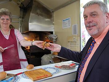 Oberbürgermeister Norbert Tessmer greift am Freitag demonstrativ zur Coburger Bratwurst, während die Flammen durch den Rost züngeln. Die Stadt rät inzwischen vom Braten über offener Flamme ab - wegen der möglichen Schadstoffbelastung. Das entsprechende Schreiben an alle Bratwurstbrater ging aber erst am Freitagmorgen in die Post. Foto: Oliver Schmidt