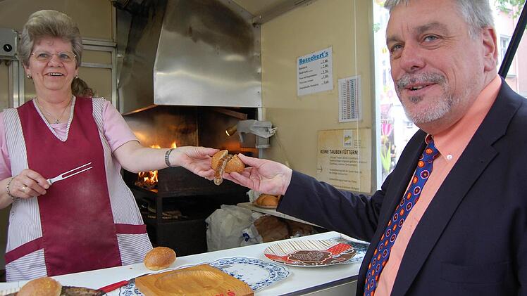 Oberbürgermeister Norbert Tessmer greift am Freitag demonstrativ zur Coburger Bratwurst, während die Flammen durch den Rost züngeln. Die Stadt rät inzwischen vom Braten über offener Flamme ab - wegen der möglichen Schadstoffbelastung. Das entsprechende Schreiben an alle Bratwurstbrater ging aber erst am Freitagmorgen in die Post. Foto: Oliver Schmidt
