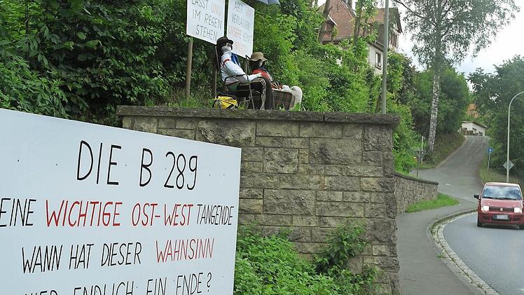 Das Plakat über den beiden Figuren, die die Kauerndorfer an der Ortsdurchfahrt der B 289 gegenüber der Einmündung nach Fölschnitz aufgestellt haben, passt zum Wetter: "Die Politik lässt uns im Regen stehen." Erst seit Dienstag steht das große Transparent unten. Fotos: Peter Müller
