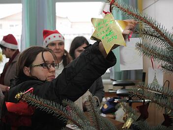 Ida Storm schmückt den Weihnachtsbaum, der die Christmas-Party des Englischkurses der Barmherzigen Brüder Gremsdorf erst so richtig feierlich werden lässt.. Auf den selbstgebastelten Sternen stehen Weihnachtsgrüße auf Englisch. Foto: S.Martin