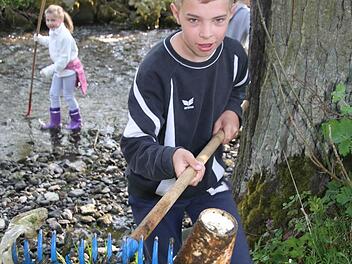Mit dem Rechen fischt Max Greim die Kaffeebacher aus dem Bach. Fotos: Sonja Adam