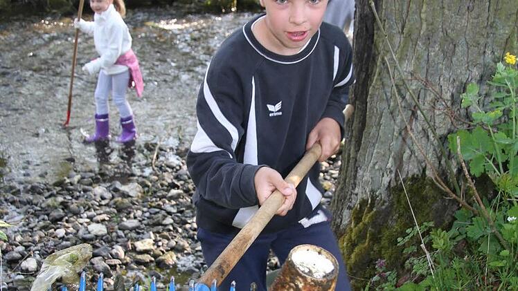 Mit dem Rechen fischt Max Greim die Kaffeebacher aus dem Bach. Fotos: Sonja Adam