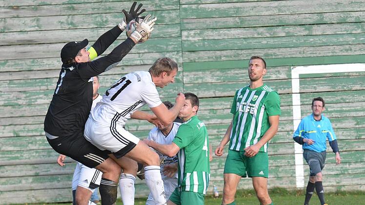 Keeper Daniel Hammer (links) vom FC Untererthal muss hier gegen  Alexander Schott vom FC Rottershausen kräftig zupacken. Schiedsrichter  Michael Solf schaut ganz genau hin. Foto: ssp