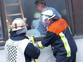 Die Feuerwehrleute bringen einen Verletzten durch ein Fenster in Sicherheit. Foto: Klaus-Peter Wulf