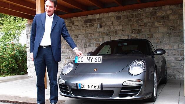 Michael Stoschek neben dem Porsche-Cabriolet seiner Frau mit dem Original-Kennzeichen und einem von ihm verwendeten verkleinerten Klebekennzeichen.Foto: Jochen Berger