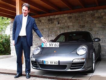 Michael Stoschek neben dem Porsche-Cabriolet seiner Frau mit dem Original-Kennzeichen und einem von ihm verwendeten verkleinerten Klebekennzeichen.Foto: Jochen Berger