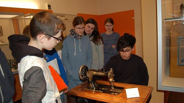 Abu Madaev (links) erl&auml;utert seinen Klassenkameraden aus der 7b, was es mit der N&auml;hmaschine im Puppenmuseum auf sich hat. Rouzbeh Saffar darf sie gleich mal ausprobieren. Foto: Helke Renner