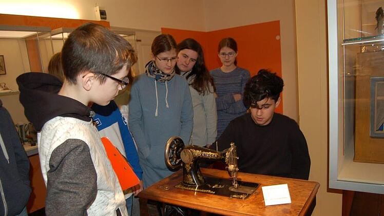 Abu Madaev (links) erläutert seinen Klassenkameraden aus der 7b, was es mit der Nähmaschine im Puppenmuseum auf sich hat. Rouzbeh Saffar darf sie gleich mal ausprobieren. Foto: Helke Renner