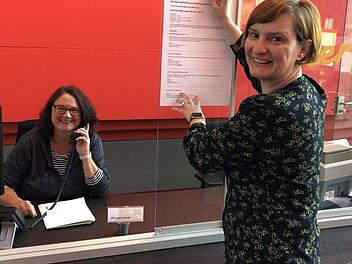 Die städtische Ehrenamtskoordinatorin Katja Heil bringt eine Information zur Nachbarschaftshilfe an, links Michaela Karrer (Mitarbeiterin an der Pforte). Foto: Stadt