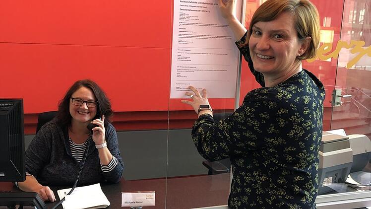Die städtische Ehrenamtskoordinatorin Katja Heil bringt eine Information zur Nachbarschaftshilfe an, links Michaela Karrer (Mitarbeiterin an der Pforte). Foto: Stadt