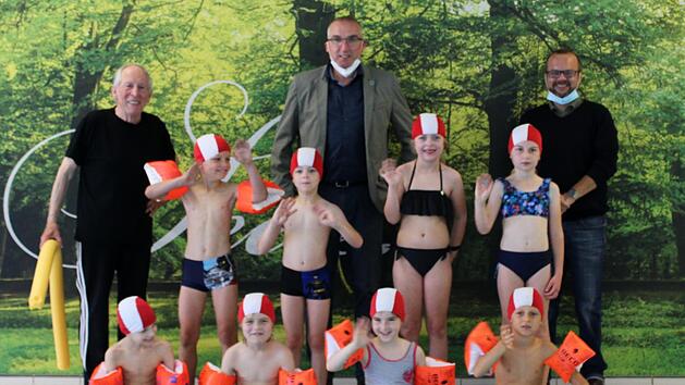 chwimmlehrer Norbert  Klodwig (von links),  Bürgermeister Andreas Sandwall und der Hoteldirektor des Kurhauses Bastian Graber, freut sich  mit den Kindern des Schwimmkurses.