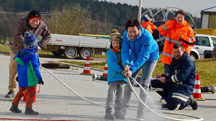 Martina Kessler und Sohn Janis versuchen mit dem Wasserstrahl, eine Wasserflasche umzuwerfen. Bernhard Kessler sorgt für genügend Nachschub mit der Kübelspritze, was Feuerwehrfrau Anna Kirchner und ihr Vater aufmerksam verfolgen. Foto: Kathrin Kupka-Hahn