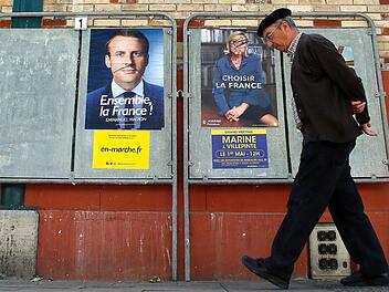 Ein Mann geht in Saint-Jean-de-Luz (Frankreich) an Wahlplakaten des sozialliberalen Präsidentschaftskandidaten Emmanuel Macron (l) und der rechtspopulistischen Präsidentschaftskandidaten Marine Le Pen vorüber. Die Franzosen wählen am 07. Mai in einer Stichwahl ihr neues Staatsoberhaupt. Foto: Bob Edme/AP/dpa