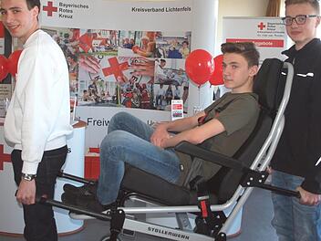 Beim BRK-Stand demonstrierte der Bundesfreiwilligendienstler Jeremias Felix (links) zusammen mit den beiden Schülern Peter Eck und Noah Schmölzing einen Tragestuhl, mit dem gebehinderte Personen transportiert werden können. Fotos: Alfred Thiereth