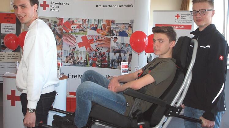 Beim BRK-Stand demonstrierte der Bundesfreiwilligendienstler Jeremias Felix (links) zusammen mit den beiden Schülern Peter Eck und Noah Schmölzing einen Tragestuhl, mit dem gebehinderte Personen transportiert werden können. Fotos: Alfred Thiereth