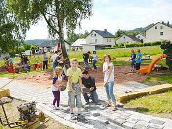 Kinder wie Eltern aus den Reihen des Obst- und Gartenbauvereins sowie vom Arbeitskreis Familienfreudiger Markt Pressig legten kräftig Hand an, um einen schönen neuen Spielplatz "Am Anger" zu gestalten. Hier packen der Vorsitzende des Obst-und Gartenbauvereins, Andreas Schorn (vorne kniend), sowie Stefan Heinlein (dahinter rechts, mit Schubkarre), der Leiter des AK, kräftig mit an. Foto: K.-H. Hofmann