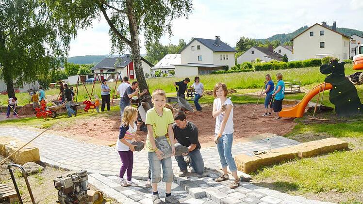 Kinder wie Eltern aus den Reihen des Obst- und Gartenbauvereins sowie vom Arbeitskreis Familienfreudiger Markt Pressig legten kräftig Hand an, um einen schönen neuen Spielplatz "Am Anger" zu gestalten. Hier packen der Vorsitzende des Obst-und Gartenbauvereins, Andreas Schorn (vorne kniend), sowie Stefan Heinlein (dahinter rechts, mit Schubkarre), der Leiter des AK, kräftig mit an. Foto: K.-H. Hofmann