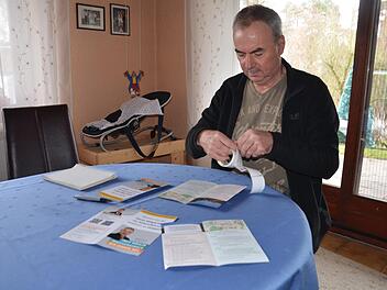 Robert Erhardt überklebt auf den restlichen 600 Flyern das Bild mit der Brücke.  Foto: Bernhard Panzer
