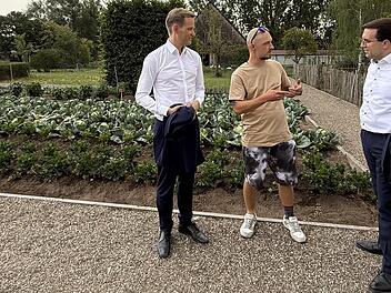 Hendrik Streeck (links) und Konrad K&ouml;rner (rechts) im Gespr&auml;ch mit einem Bewohner, der die landwirtschaftlichen Projekte der Laufer M&uuml;hle vorstellt. Birgit V&ouml;lker