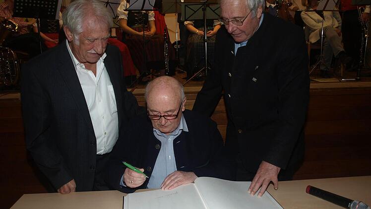 In das Ehrenwallfahrtsbuch trug sich Günther Kühr ein. Er war bereits zum 45. Mal dabei. Ehrenwallfahrtsführer Otmar Seidl (links) und sein Nachfolger Otmar Lutz (rechts) sind stolz und sehen ihn als Vorbild für viele Wallfahrer, die jedes Jahr aufbrechen. Foto: Stefan Geiger