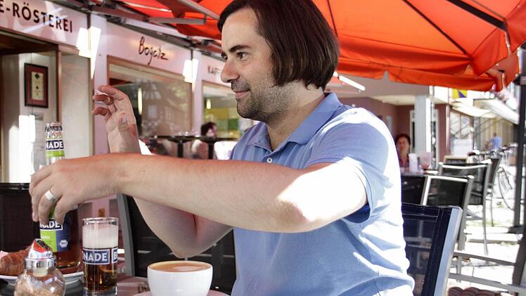 Entspannt winkt der Kandidat im Café einem Baby im Buggy ohne dutzi-dutzi-Getue freundlich zu.