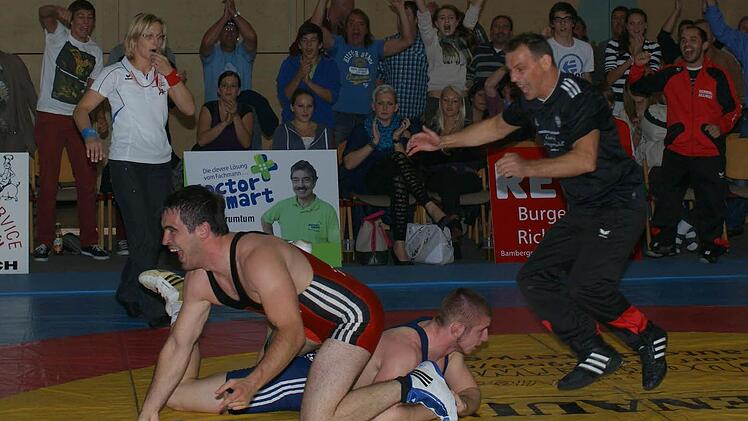 Der Burgebracher Spitzenringer Michael Giehl (l.) freut sich über seinen Schultersieg. Das waren wichtige vier Punkte für seine Manschaft im Kampf gegen den AC Köln, den der TSV mit 22:17 überraschend gewann. Trainer Alexander Winkler (r.) und die Fans in der Windeck-Halle jubeln.  Foto: privat