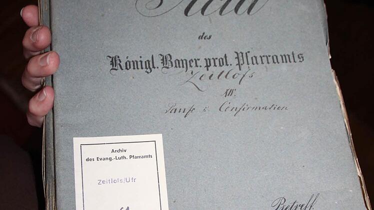 Joachim Weichert und Leo Übelacker aus Zeitlofs durchforsteten alte Kichenunterlagen. Foto: Ulrike Müller