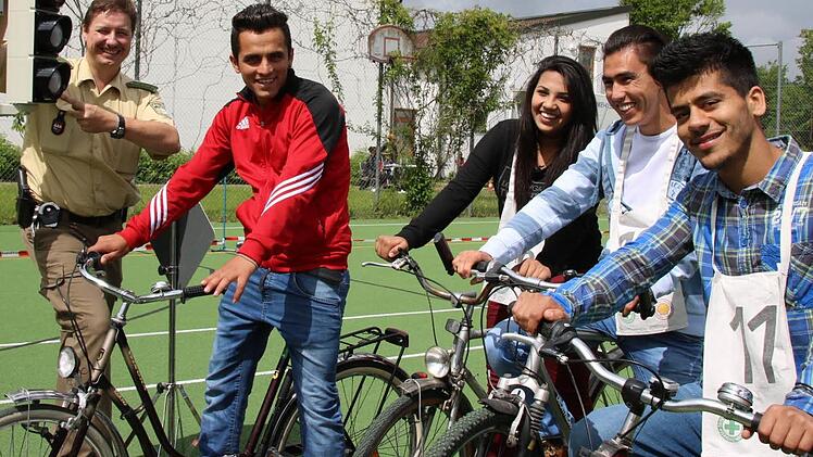 Verkehrserzieher Matthias Kleren (von links) erläutert den Flüchtlingen Shoaib Hamidi, Suzan Ahmad, Aman Mohammadi und Ahmad Schoaib Saqebi unter anderem das richtige Verhalten an einer Kreuzung mit Ampel.