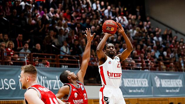 Der W&uuml;rzburger Cameron Wells (links) kommt zu sp&auml;t und kann den Distanzwurf von Jordan Crawford nicht mehr verhindern. Mit 23 Punkten, davon f&uuml;nf Dreiern, war der Bamberger Neuzugang auch im zweiten Spiel der beste Werfer seines neuen Teams. Foto: Daniel L&ouml;b