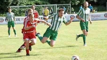 Der Rothenkirchner Angreifer (grünes Trikot) kommt zu Fall, der Reitscher Spieler schnappt sich den Ball.