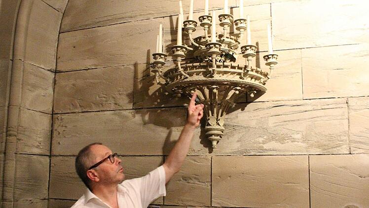 Kirchenpfleger Helmut Kollo zeigt einen der Kandelaber, die allesamt mit einer Farbschicht überzogen sind. Foto: Ulrike Nauer